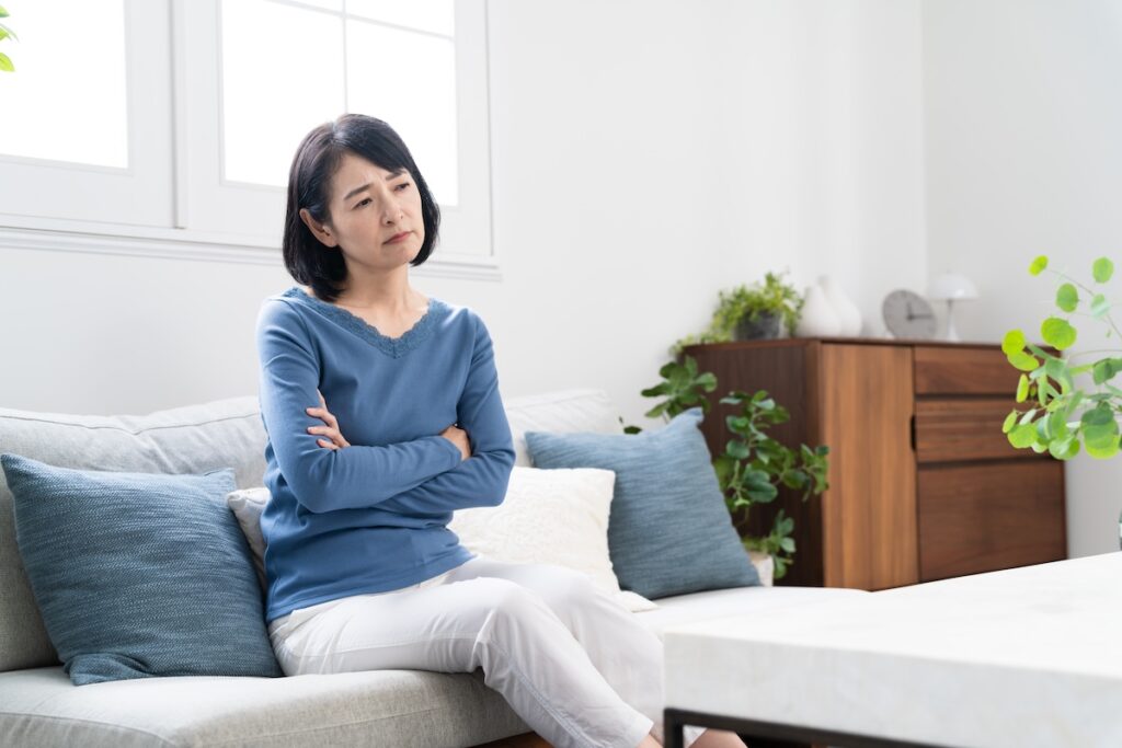 ソファーに座って悩んでいる女性